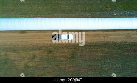Luftaufnahme des 4x4 Pickup-LKW, der durch Weizenanbau-Feld mit Silosäcken auf der Straße fährt. Argentinien Stockfoto