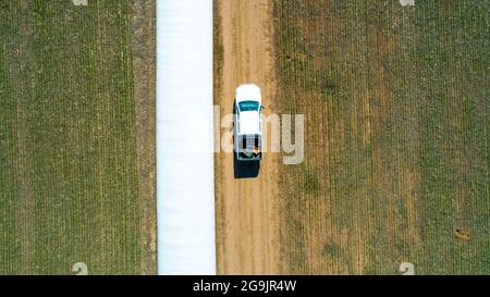 Luftaufnahme des 4x4 Pickup-LKW, der durch Weizenanbau-Feld mit Silosäcken auf der Straße fährt. Argentinien Stockfoto
