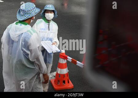 Tokio, Japan. Juli 2021. Im Regen stehen Freiwillige in Regenmänteln an der Bushaltestelle. Quelle: Swen Pförtner/dpa/Alamy Live News Stockfoto