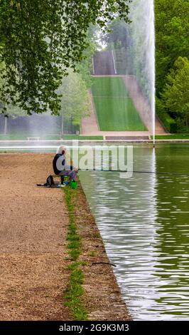 Älterer brauner Mann, der in einem See mit formellen Gärten in Sceaux, Frankreich, fischt Stockfoto