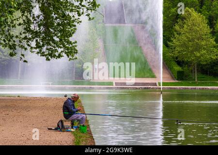 Älterer brauner Mann, der in einem See mit formellen Gärten in Sceaux, Frankreich, fischt Stockfoto