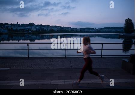 Dortmund, Deutschland. Juli 2021. Ein Läufer ist am Ufer des Phoenix Lake in der Morgendämmerung. Quelle: Bernd Thissen/dpa/Alamy Live News Stockfoto