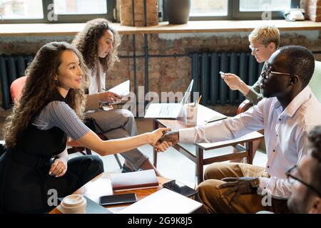 Zwei junge Mitarbeiter, die sich nach der Unterzeichnung des Geschäftsvertrags die Hände schüttelten Stockfoto