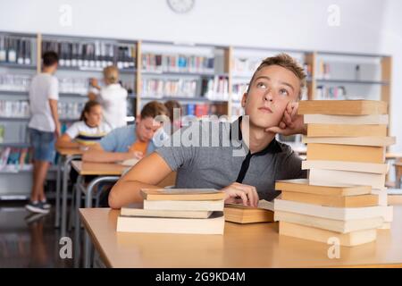 Gelangweilter Schuljunge in der College-Bibliothek Stockfoto