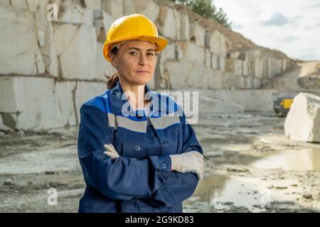 Ernsthafte Bergarbeiterin oder Baumeisterin in Uniform und Hardhat, die die Arme auf der Brust kreuzten Stockfoto