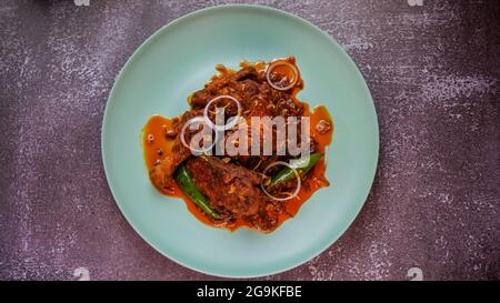 Hühnchen in trockenem würzigen roten, mit Zwiebelring und grünem Chili garnierten, roten Paprikaschoten. Stockfoto