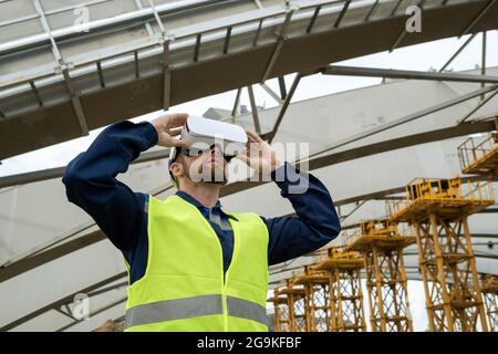 Der junge Ingenieur, der Virtual-Reality-Brillen verwendet, arbeitet auf der Baustelle Stockfoto