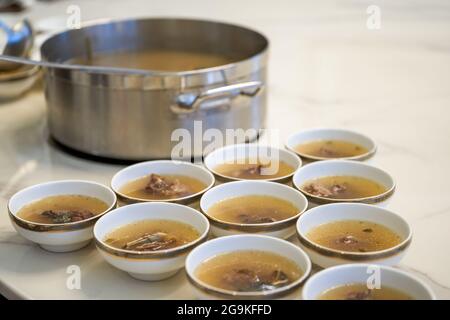 Der Kellner im Hotel teilt die gepanzerte Fischsuppe und die kantonesische Suppe für die Gäste auf. Stockfoto