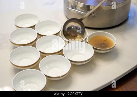 Der Kellner im Hotel teilt die gepanzerte Fischsuppe und die kantonesische Suppe für die Gäste auf. Stockfoto