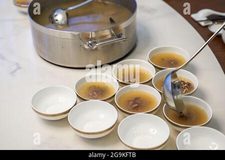 Der Kellner im Hotel teilt die gepanzerte Fischsuppe und die kantonesische Suppe für die Gäste auf. Stockfoto