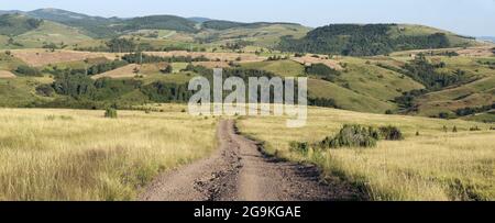 Schotterstraße durchquert die ländliche Landschaft in Sjenica, Serbien Stockfoto