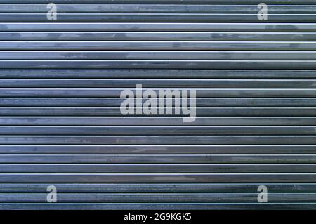 Hintergrund aus Stahlrohren. Geformte Stahlrohre. Mehrere Metallrohre liegen nebeneinander. Linien durch Rohre erstellt. Einen Zaun machen. Stockfoto