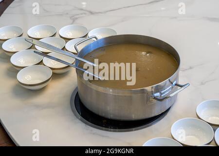 Der Kellner im Hotel teilt die gepanzerte Fischsuppe und die kantonesische Suppe für die Gäste auf. Stockfoto