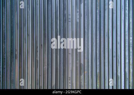 Hintergrund aus Stahlrohren. Geformte Stahlrohre. Mehrere Metallrohre liegen nebeneinander. Linien durch Rohre erstellt. Einen Zaun machen. Stockfoto