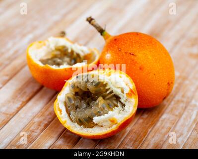 Ganze und halbierte passiflora-Früchte auf Holzgrund Stockfoto