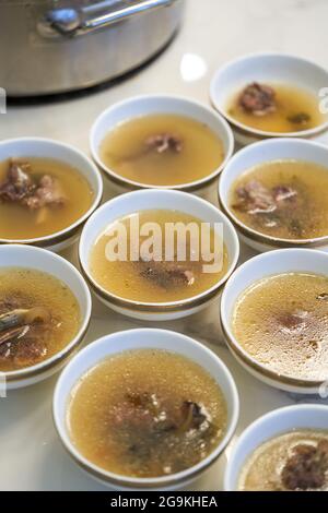 Der Kellner im Hotel teilt die gepanzerte Fischsuppe und die kantonesische Suppe für die Gäste auf. Stockfoto