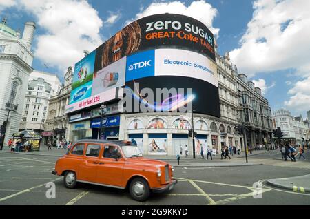 LONDON, ENGLAND - 27. MAI: Ein rotes Taxi überquert die ikonischen Videowerbung-Werbetafeln des Piccadilly Circus. Es ist ein berühmter öffentlicher Raum in Londons Stockfoto