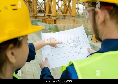 Nahaufnahme von zwei Ingenieuren, die auf Blaupause zeigen und die Bauarbeiten im Freien kontrollieren Stockfoto