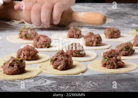 Prozess der Herstellung von hausgemachten Knödeln, Ravioli oder Pelmeni mit Hackfleisch. Stockfoto