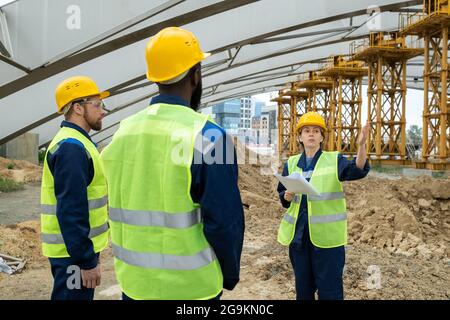 Eine Gruppe von Ingenieuren, die vor Ort stehen und die Arbeit eines zukünftigen Projekts im Team besprechen Stockfoto