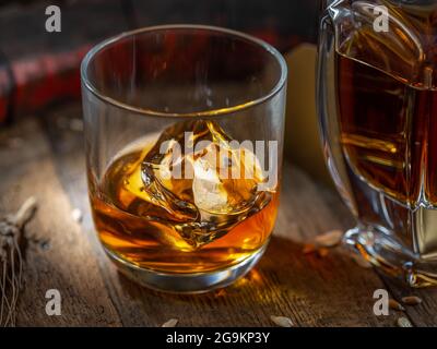 Karaffe Whisky und Glas Whisky auf altem Holzfass auf dunklem Hintergrund. Stockfoto