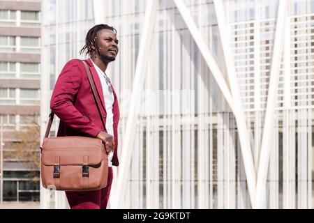 Eleganter afrikanischer Geschäftsmann mit Aktentasche geht durch die finanzielle Innenstadt der Stadt, Platz für Text kopieren Stockfoto