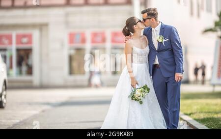 Schönes Paar, das sich mitten in der Stadt küsst. Sie sind gerade verheiratet und lassen sich ein Foto zum Album machen. Stockfoto