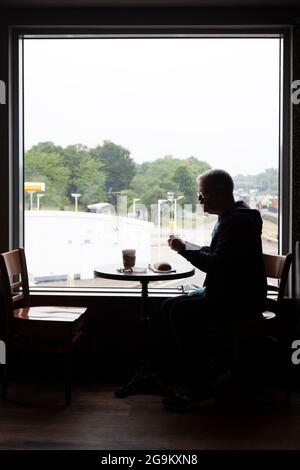 Silhouette des Mannes beim Essen im Restaurant in London Gateway an der M1, Großbritannien Stockfoto