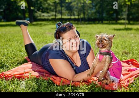 Body positive glückliche Frau mit yorkshire Terrier geht im Garten. Stockfoto