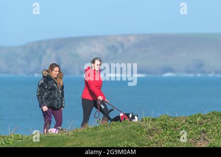 Zwei Freundinnen gehen mit ihren Hunden auf dem Küstenwanderweg in Newquay in Cornwall. Stockfoto