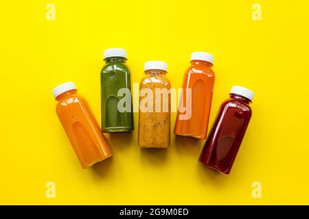 Frische Säfte oder Smoothies von Obst und Gemüse in Flaschen auf gelbem Hintergrund. Das Konzept einer gesunden Ernährung oder Entgiftung. Frische Bio-Zutaten Stockfoto