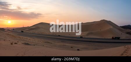 Sanddünen in Badr, Madinah, Saudi-Arabien bei Sonnenuntergang, durch die die Autobahn führt. Tourismus in KSA Stockfoto