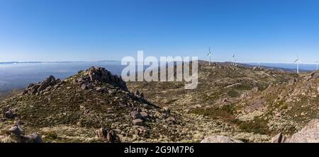 Ultra-Panoramablick auf die Caramulo Berge, mit Windturbinen und blauem Himmel, Serra da Estrela Berge als Hintergrund, in Viseu, Portugal Stockfoto