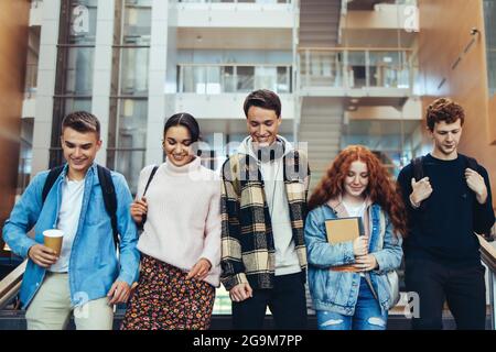 Junge Studenten gehen für ihre Klasse. Gruppe junger Menschen, die auf dem College-Campus zusammenlaufen. Stockfoto