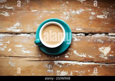 Draufsicht Studiofoto von heißem Kaffee mit Milch in blauer Porzellanbecher und Untertasse auf Vintage-Holzfläche mit Platz für Text, Foto im rustikalen Stall Stockfoto