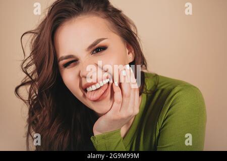 Nahaufnahme Porträt einer jungen glücklichen Brünette Frau mit ernstem Gesichtsausdruck stehend seitlich und Blick direkt auf die Kamera in hellgrünem Hemd i Stockfoto