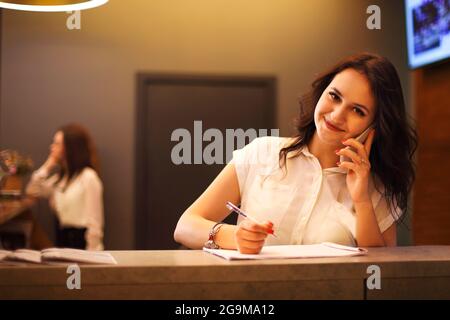 Brünette Frau Rezeptionistin arbeitet in der Rezeption des Schönheitssalons Stockfoto