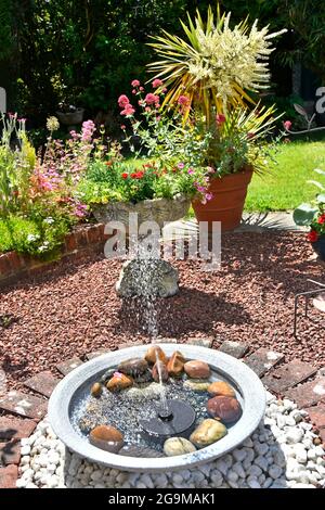 Solar-Panel Mini-Brunnen Funktion auf der Oberseite der gefüllten im Sommergarten Teich Enkel Sicherheit Fragen cordyline Topf Blume über England Großbritannien Stockfoto