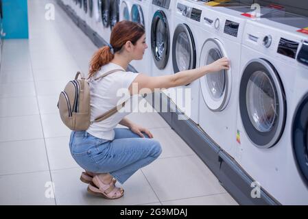 Kaukasische Frau wählt eine Waschmaschine in einem Haushaltswarenladen Stockfoto