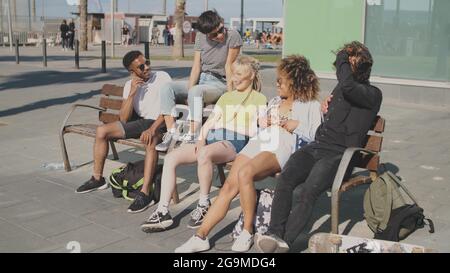Inhalte multiethnischer Freunde auf der Straßenbank Stockfoto
