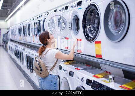 Kaukasische Frau wählt eine Waschmaschine in einem Haushaltswarenladen Stockfoto