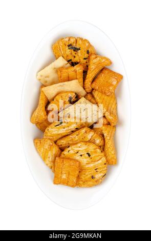 Senbei, japanische Reiscracker, in einer weißen ovalen Schüssel. Auch halbherzige, knusprige, mundgerechte, herzhafte Snacks in verschiedenen Formen und Größen, leicht gesalzen. Stockfoto
