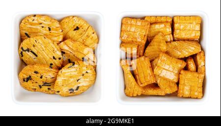 Senbei, japanische Reiscracker in weißen quadratischen Schalen. Auch halbherzige, knusprige, mundgerechte, herzhafte Snacks in verschiedenen Formen und Größen, leicht gesalzen. Stockfoto