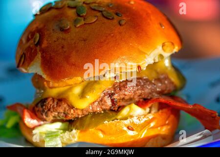 Nahaufnahme eines Burgers in einem Restaurant mit Zwiebelringen, Käse und Gemüse Stockfoto