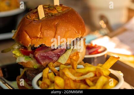 Nahaufnahme eines Burgers in einem Restaurant mit Zwiebelringen, Käse und Gemüse Stockfoto