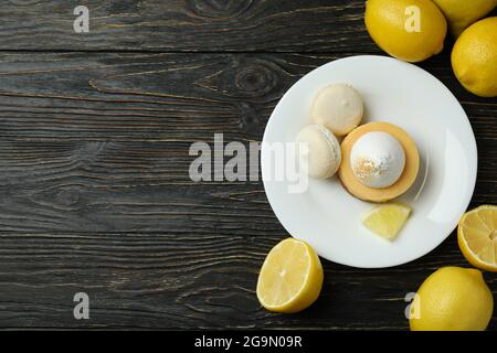Teller mit Cupcake und Makronen und Zitronen auf Holztisch Stockfoto