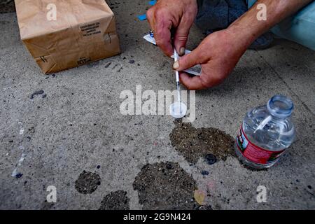 Skid Row, Downtown Central Los Angeles, Kalifornien, USA, Juni 2021. Scotty schlägt drei Dimes Meth pro Tag, Straßensprache für Injektion für 30 USD Kristallmeth. Er verdient sein Geld, indem er die von den Organisationen überbrachte Hand verkauft. Beim Nadelwechsel bekommt er manchmal einen Beutel mit 40 Nadeln. Er benutzt selbst nur 4 und verkauft den Rest für einen Dollar pro Stück. Hier schießt er für 5 US-Dollar Meth auf.Los Angeles steht vor einer humanitären Krise, die sie noch nie erlebt hat, da Obdachlosigkeit und Drogenmissbrauch in dem Gebiet namens "Skid Row" zunehmen. Die Covid-19-Pandemie trug als Immobilienpreise zu dem Problem bei Stockfoto