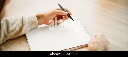 Banner eines Kakausers Hände Schreiben in einem leeren Papier Notizbuch mit einem Stift, Projektplanung, Erstellen einer Einkaufsliste. Notizblock mit Platz für Text Stockfoto