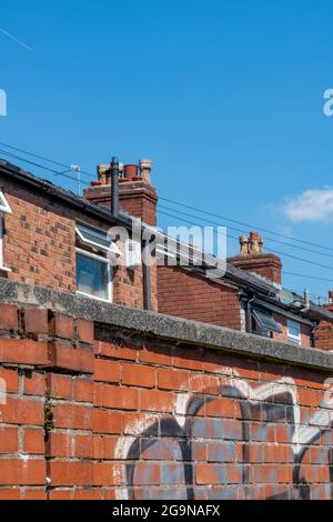 Die Häuser der roten Ziegelindustrie befinden sich auf einer Terrasse im Großraum Manchester, auf der Graffiti an die Wand gesprüht wurden. Straßenfotografie Straßenkunst Stockfoto