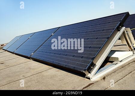 Große elektrische Solarzellen auf dem Dach bei Sonnenaufgang mit klarem blauen Himmel Stockfoto